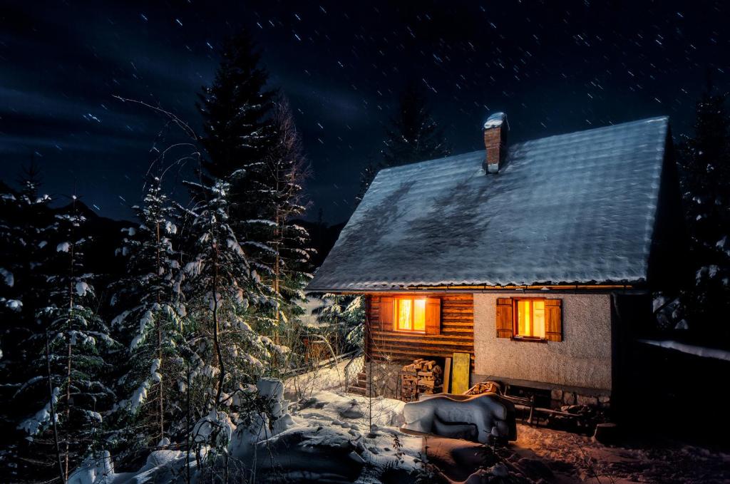 uma cabana de madeira na neve à noite em Chalet Romantic em Zgornje Jezersko