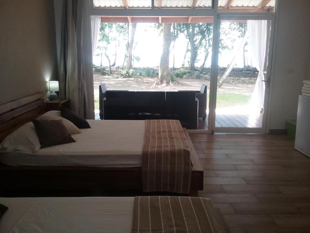 1 dormitorio con 2 camas y ventana grande en Cahuita Inn, en Cahuita