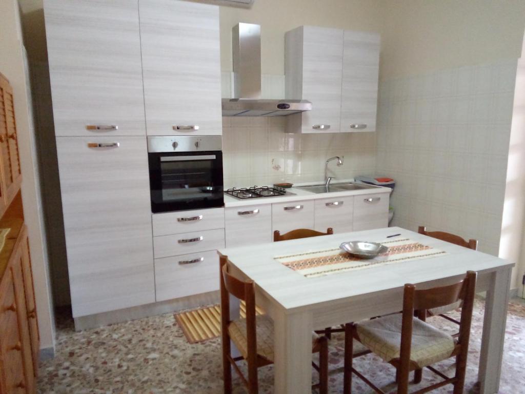 cocina blanca con mesa y fregadero en Casa di Jerry Castellabate 2, en Santa Maria di Castellabate