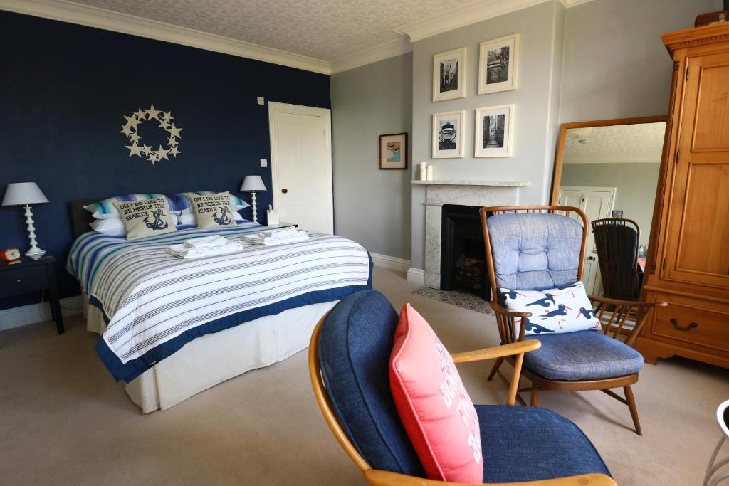 um quarto com uma cama, 2 cadeiras e uma lareira em Saxon Villa em Robin Hood's Bay