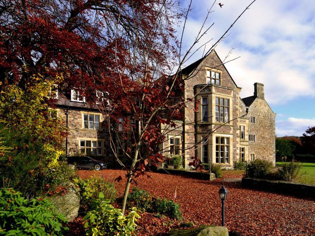 an old stone house with a tree in front of it at Clennell Hall Country House - Near Rothbury - Northumberland in Alwinton