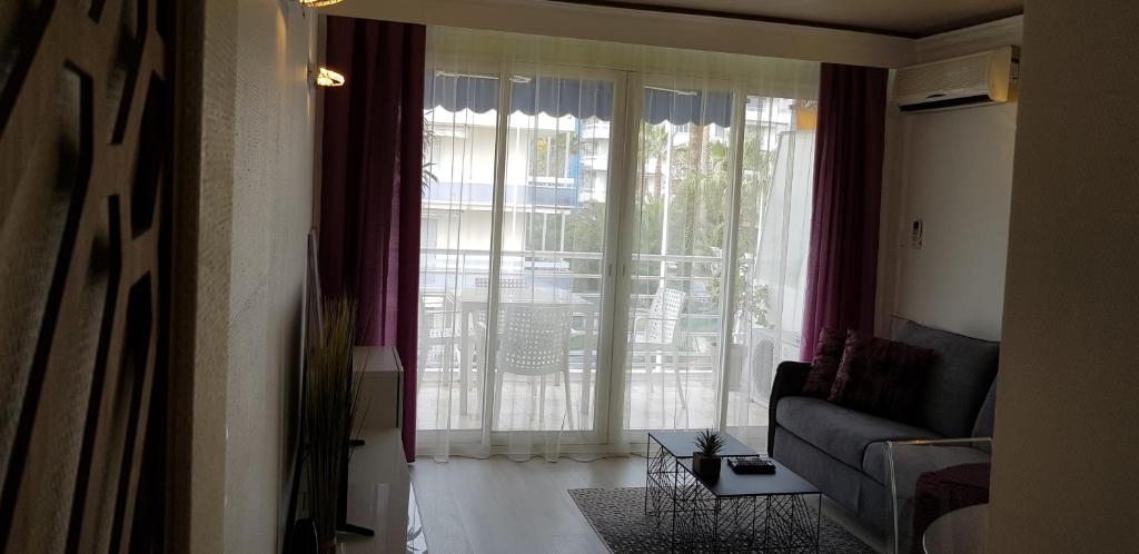 a living room with a couch and a large window at Palm beach Cannes Azur in Cannes
