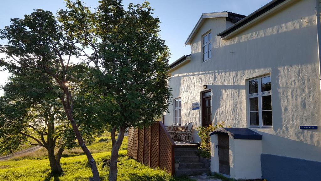 une maison blanche avec des arbres devant elle dans l'établissement Korpudalur HI Hostel, à Flateyri