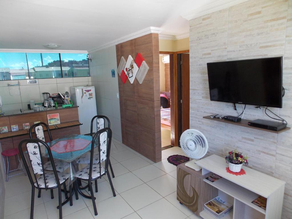 cocina y sala de estar con mesa y TV en Lindo apartamento, pertinho do mar e com vista, en Maragogi