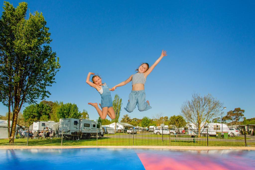 two young people jumping in the air over a swimming pool at NRMA Ballarat Holiday Park in Ballarat