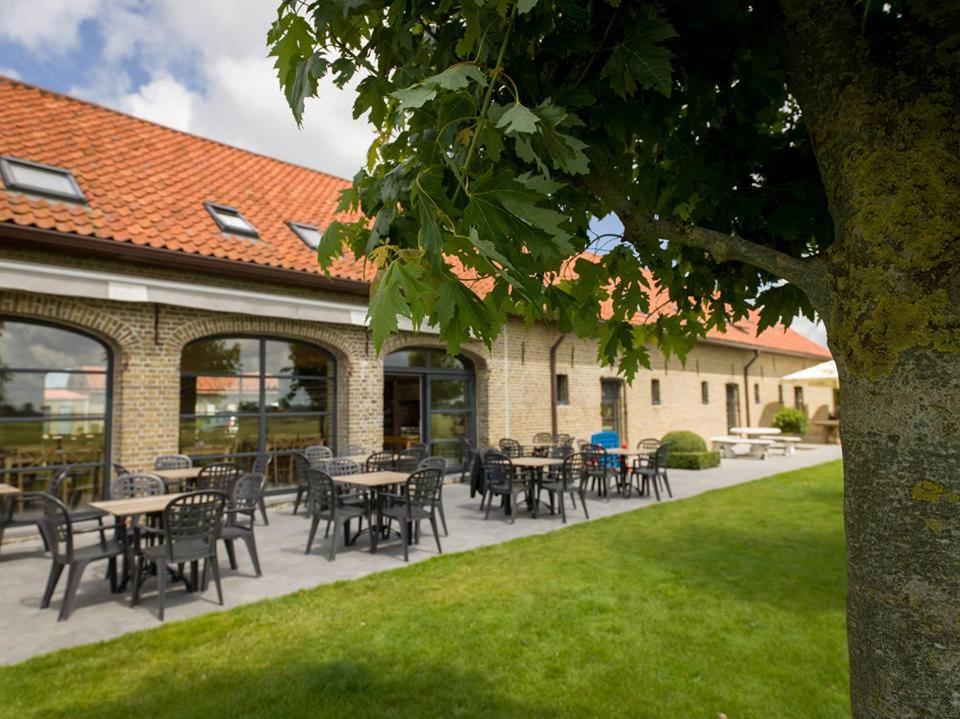 a patio with tables and chairs in front of a building at hoevehotel ter haeghe in Gistel