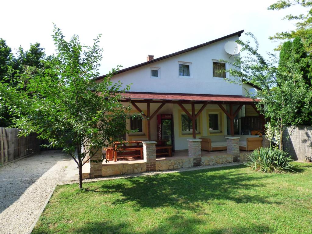 a white house with a porch and a yard at Csikós Vendégház in Zamárdi