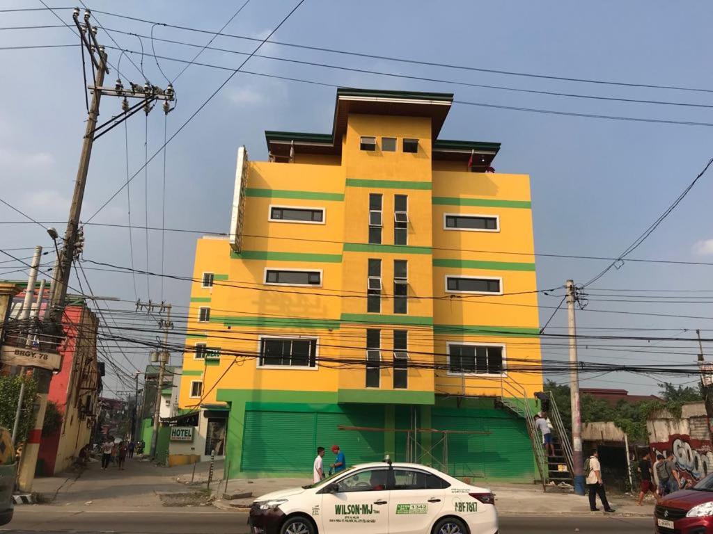 a yellow and green building with a car parked in front of it at Meaco Royal Hotel - Malabon in Manila