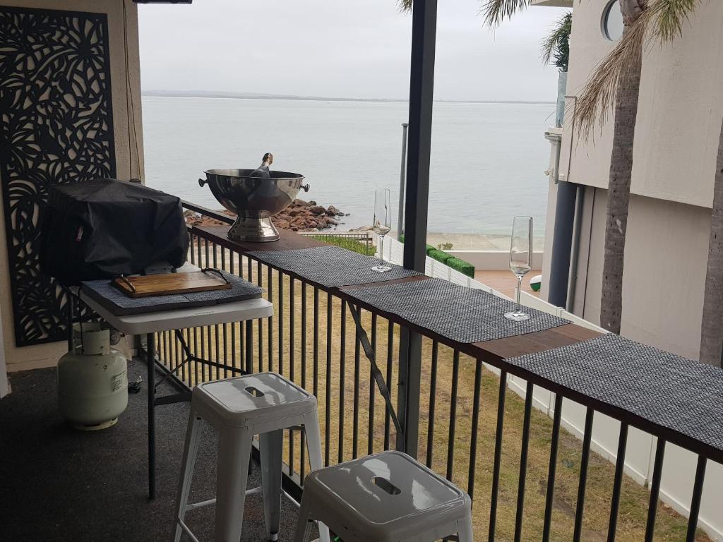 een balkon met een tafel en uitzicht op de oceaan bij Waterfront Location - 2 Bed Apartment in Corlette, Port Stephens - Sleeps 4 in Corlette