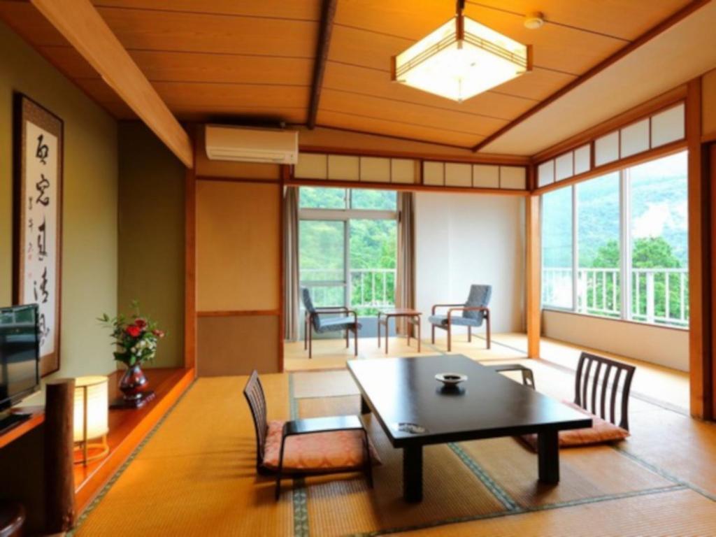 een woonkamer met een tafel en stoelen bij Unzen Iwaki Ryokan in Unzen