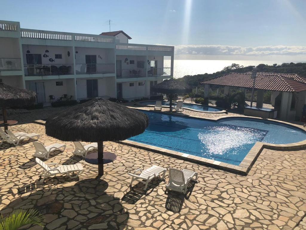 a swimming pool with umbrellas and chairs in front of a building at Apartamento em Jacumã PB in Jacumã