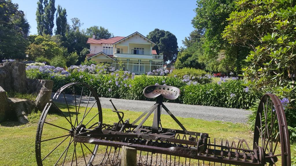 un jardin avec une balance en face d'une maison dans l'établissement Arles Historical Homestead, à Whanganui