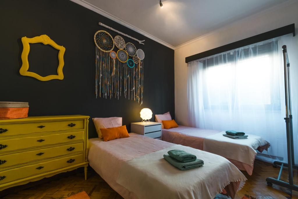 a bedroom with two beds and a dresser and a window at Lisboa Manaia Home in Lisbon