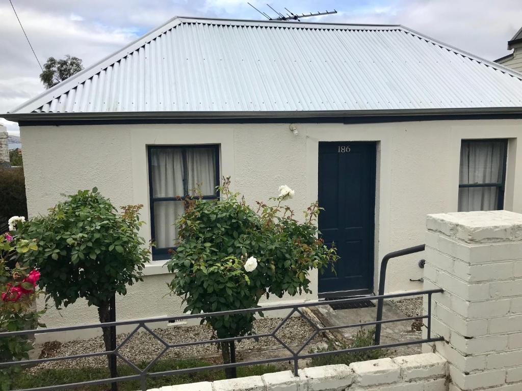 una casa blanca con una puerta negra y dos ventanas en Omaroo House - panoramic water views en Hobart