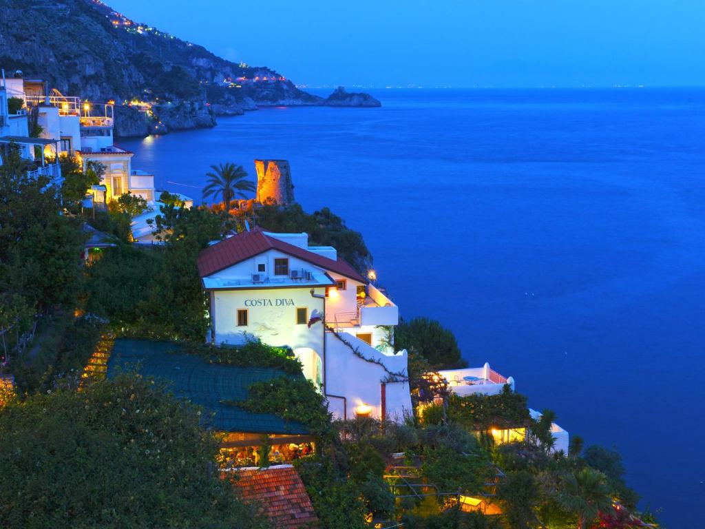 a town on a hill with the ocean at night at Hotel Costa Diva in Praiano