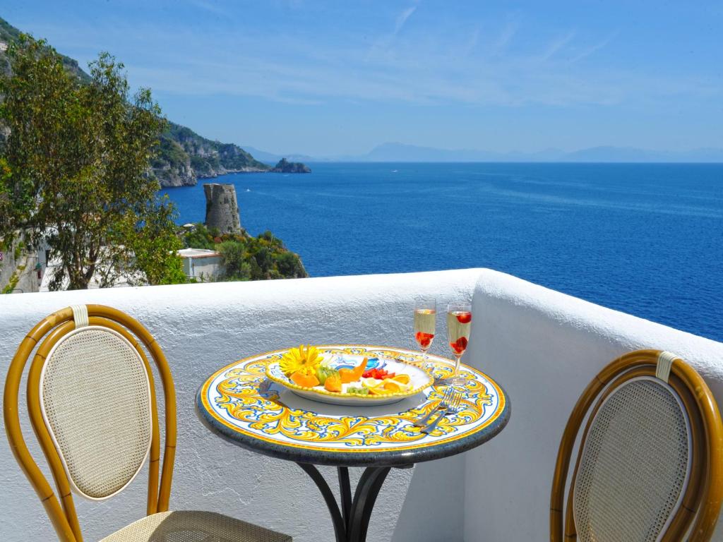 a table with a bowl of food on a balcony with the ocean at Hotel Costa Diva in Praiano