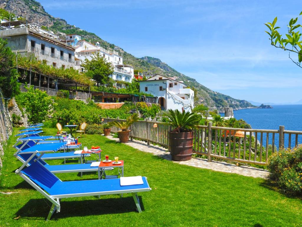 a row of blue tables on a lawn with the ocean at Hotel Costa Diva in Praiano