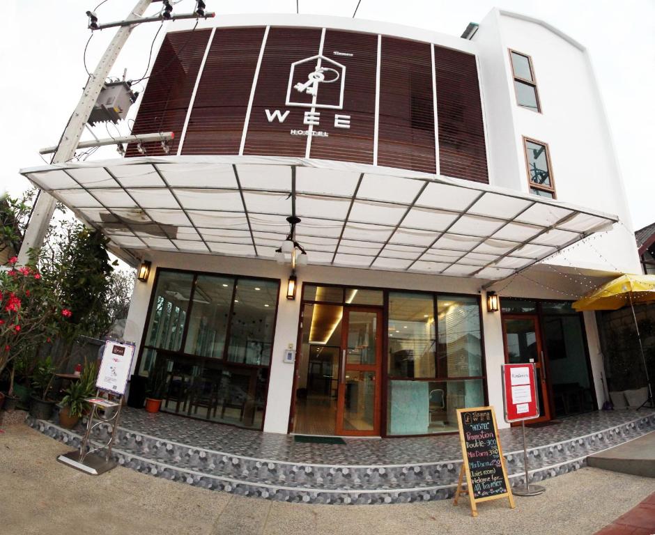 a building with a sign in front of it at WEE HOSTEL in Kanchanaburi