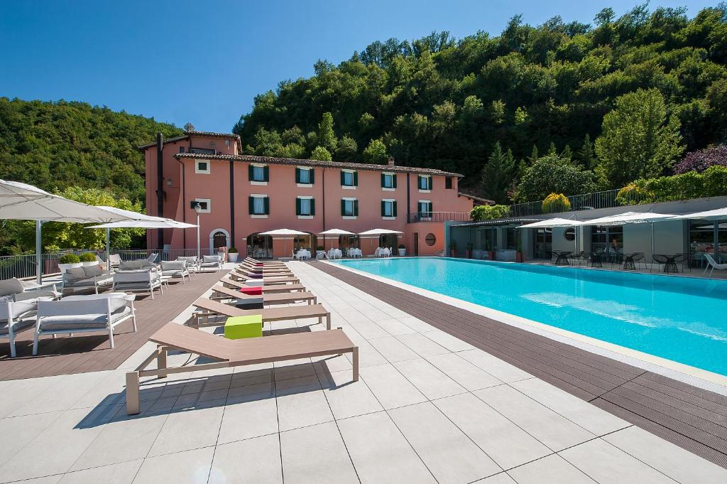 una piscina con tumbonas y un hotel en La Reggia Sporting Center Hotel, en Cascia