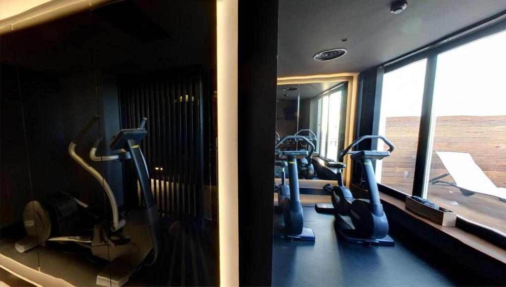 a gym with treadmills and ellipticals in front of a mirror at El Môderne Hotel in Gijón