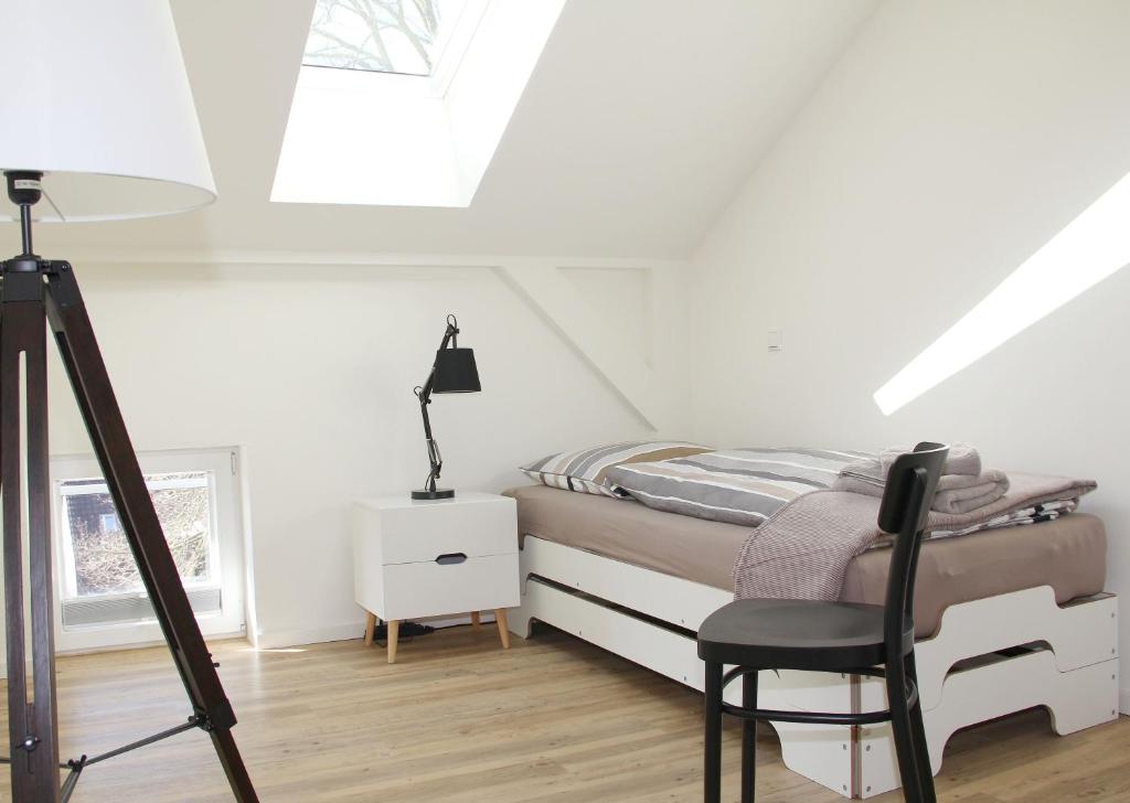 a white bedroom with a bed and a chair at Quartier36 in Schleswig