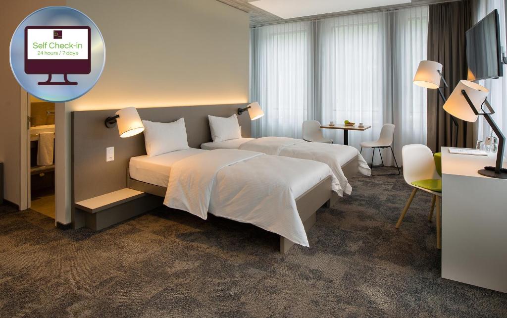 a hotel room with two beds and a tv at b_smart motel Landquart in Landquart