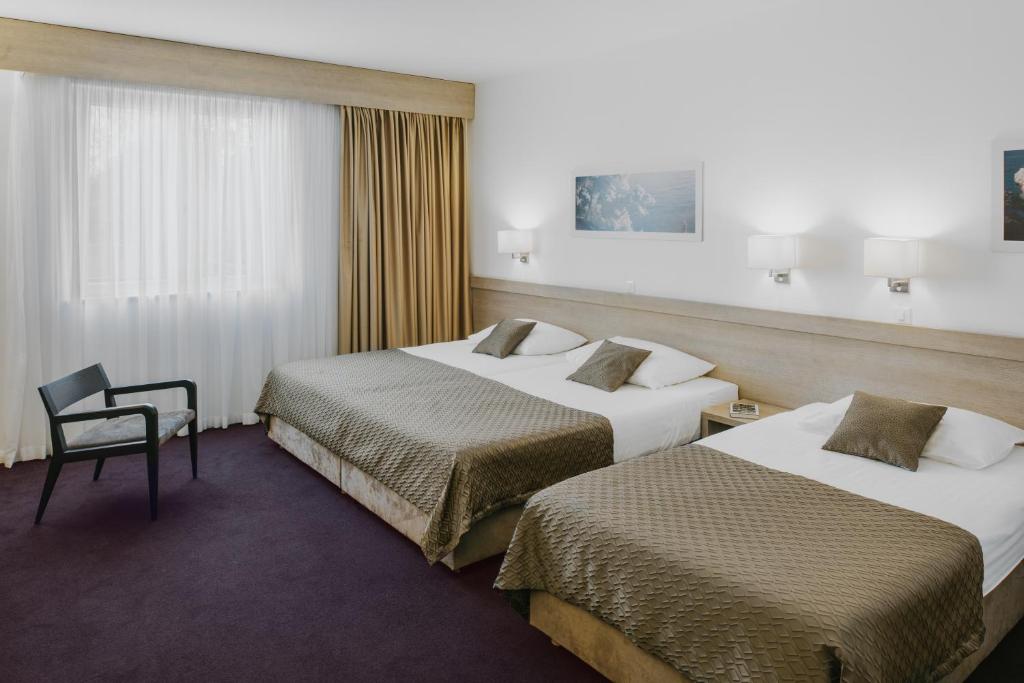 a hotel room with two beds and a chair at Hotel Adria in Dubrovnik