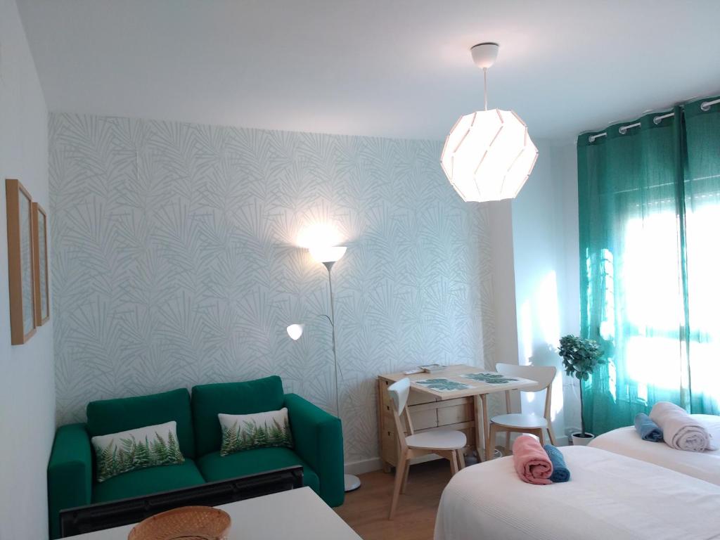 a hotel room with a green couch and a table at Estudio San Felipe in Cádiz