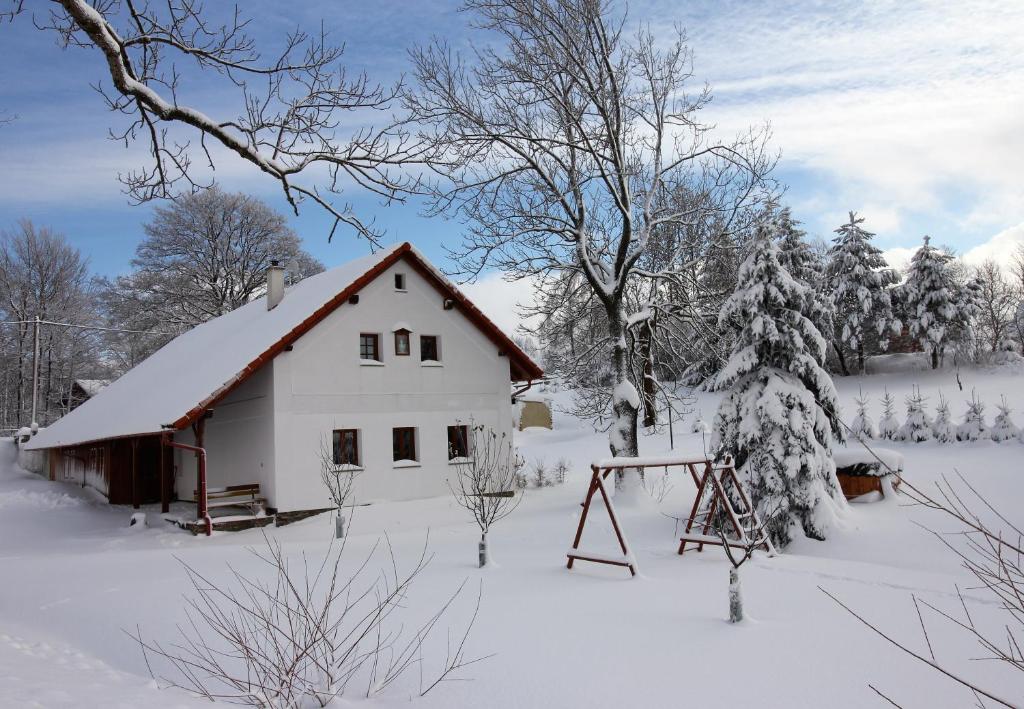 een witte schuur in de sneeuw met een schommel bij Apartmány u Knajflů in Petrovice