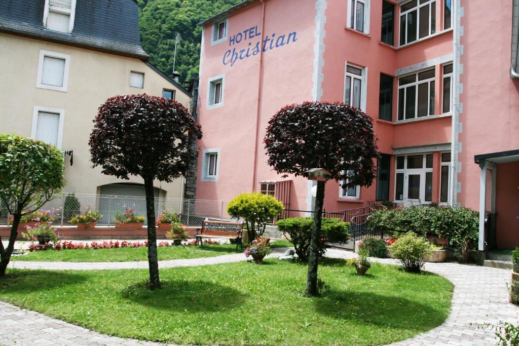 a group of trees in front of a pink building at Hotel Christian in Cauterets