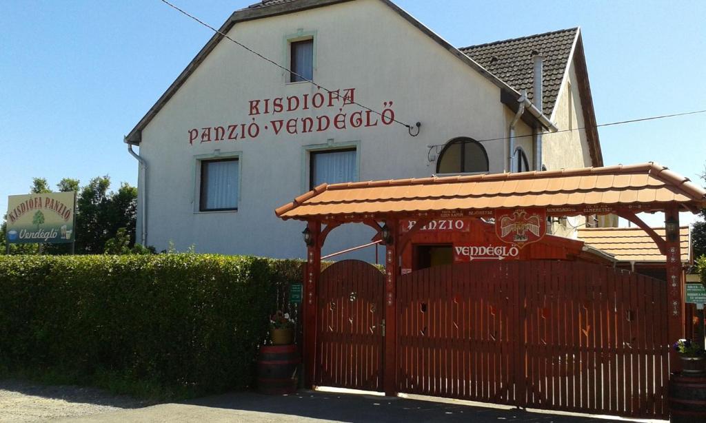 a building with a gate in front of a house at Kisdiófa Panzió és Vendéglő in Vajdácska