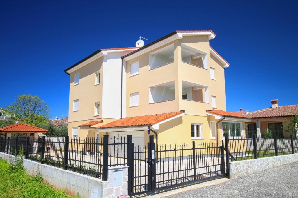 a yellow house with a black fence at Dragan K1 in Medulin