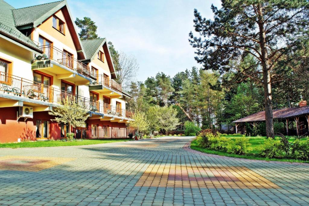 Hotel exterior with balconies, surrounded by trees and paved walkway.