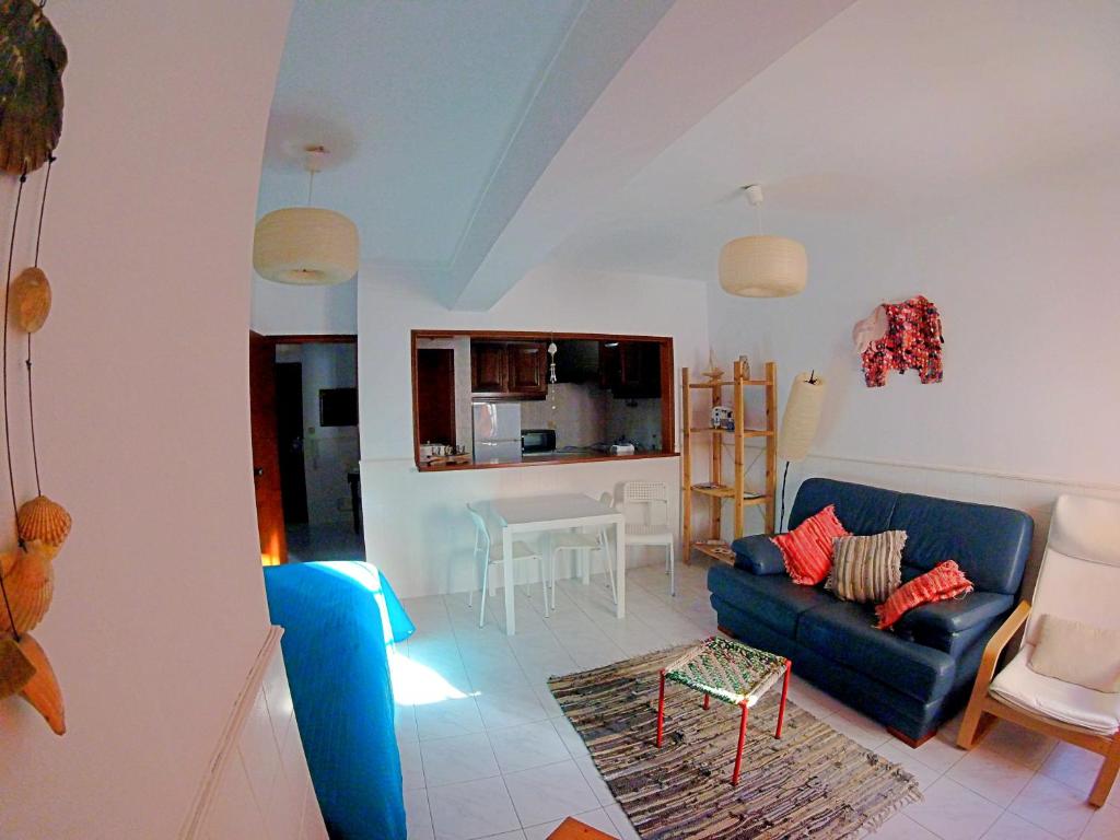 een woonkamer met een blauwe bank en een keuken bij Studio Martins in Praia da Areia Branca