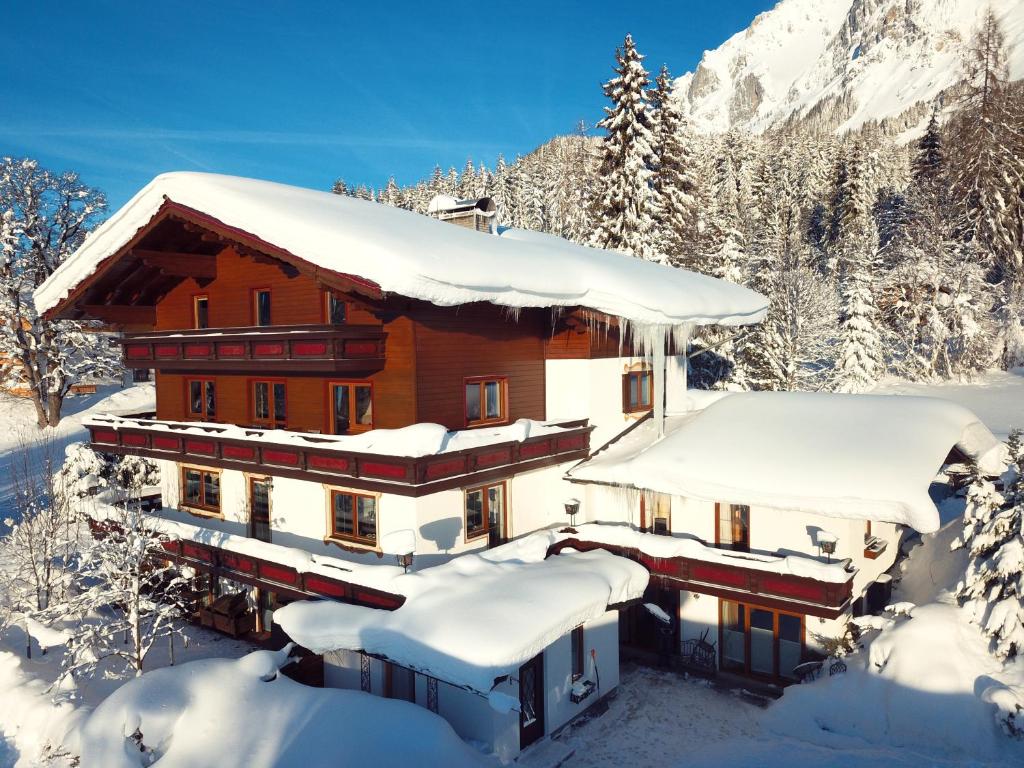 a house covered in snow in the mountains at Pension Dachsteinhof in Ramsau am Dachstein