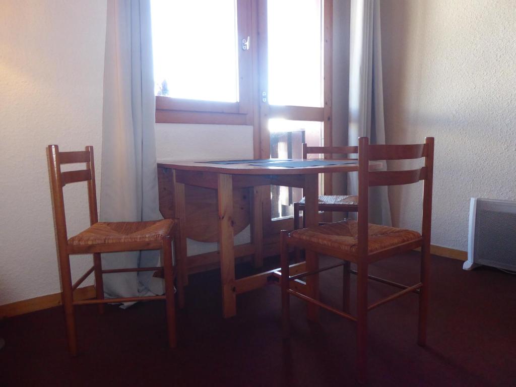 a wooden table with two chairs and a table with a window at La Maison Tresallet in Les Coches