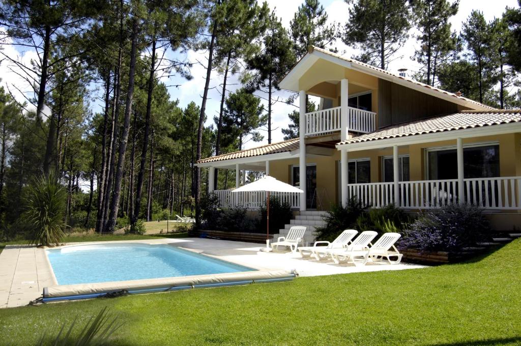 una casa con piscina frente a ella en Lagrange Vacances - Eden Parc Golf, en Lacanau-Océan