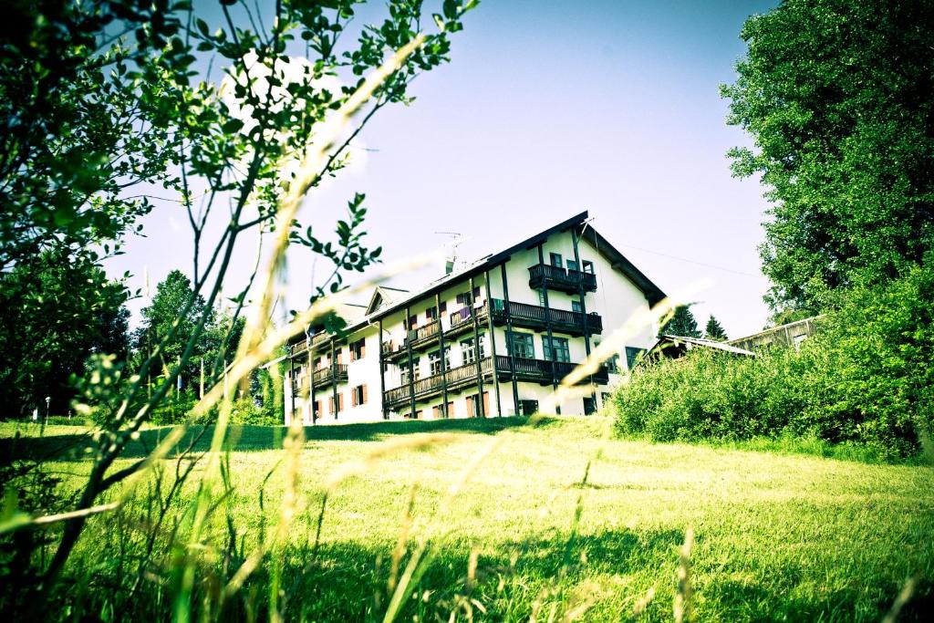 ein großes Haus auf einem grasbewachsenen Feld mit Bäumen in der Unterkunft Jugendherberge Oberstdorf in Oberstdorf
