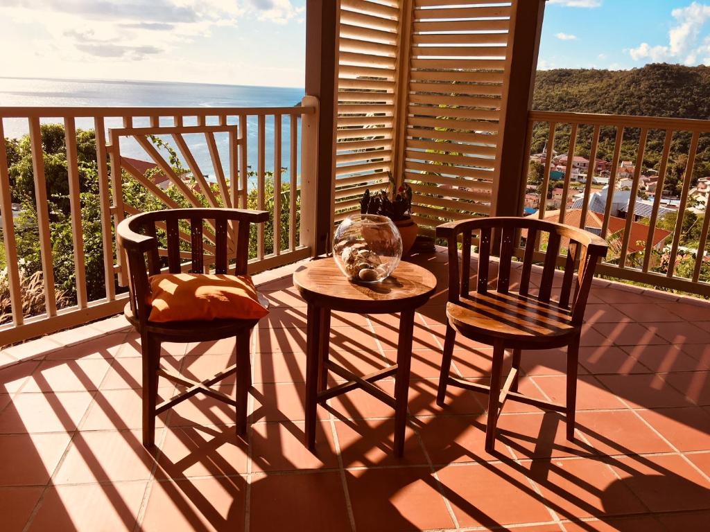 einen Tisch und zwei Stühle auf einem Balkon mit Meerblick in der Unterkunft La Villa Kanel in Les Anses-dʼArlets