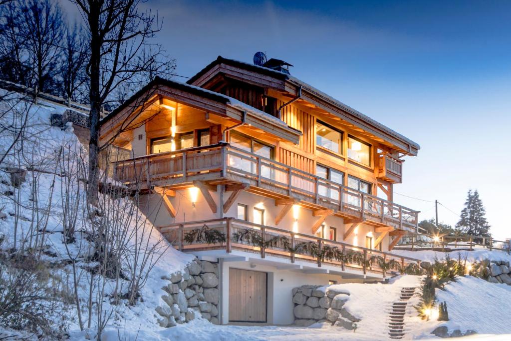 a house in the snow with lights on at Chalet Caprice in Combloux