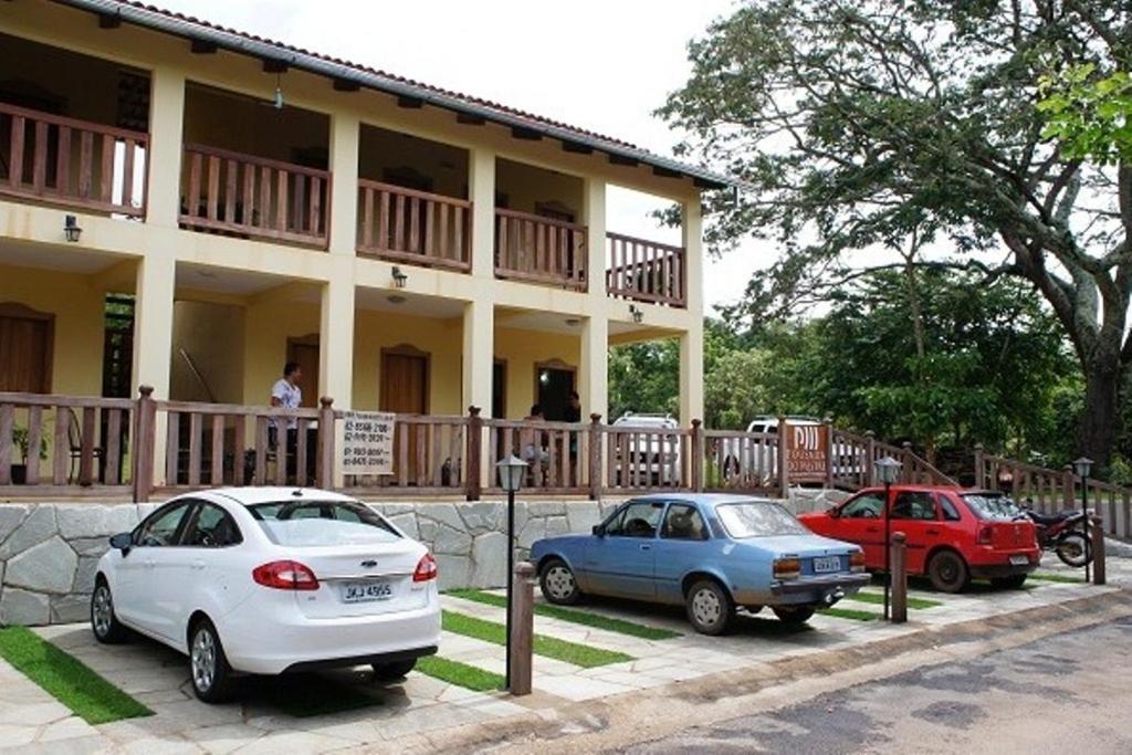 dos autos estacionados en un estacionamiento frente a un edificio en Pousada Do Mestre, en Pirenópolis