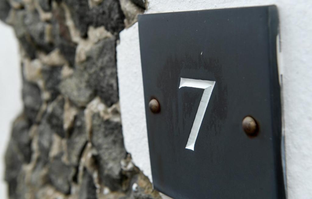 a black sign with the number on a stone wall at 7 Mersey Street, Borth-y-Gest in Porthmadog