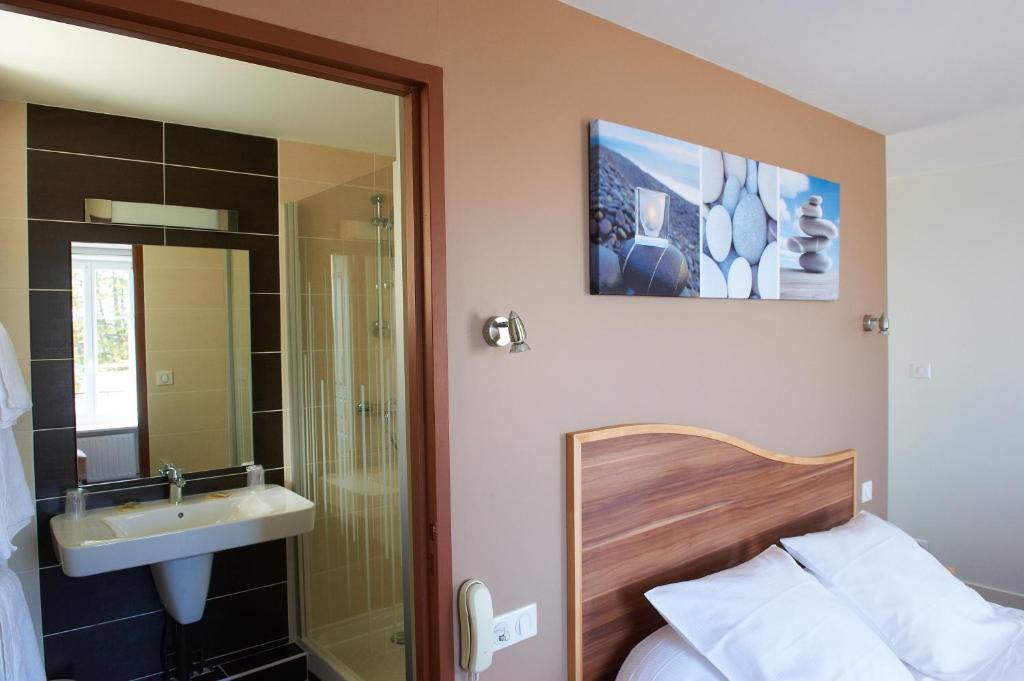 een badkamer met een bed, een wastafel en een spiegel bij Logis Hotel Belle-Vue in Fouesnant