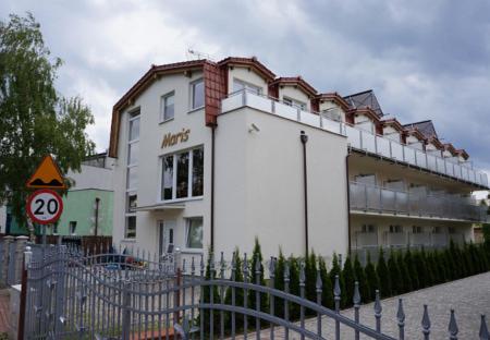a white building with a fence in front of it at Maris Pokoje Gościnne in Łeba