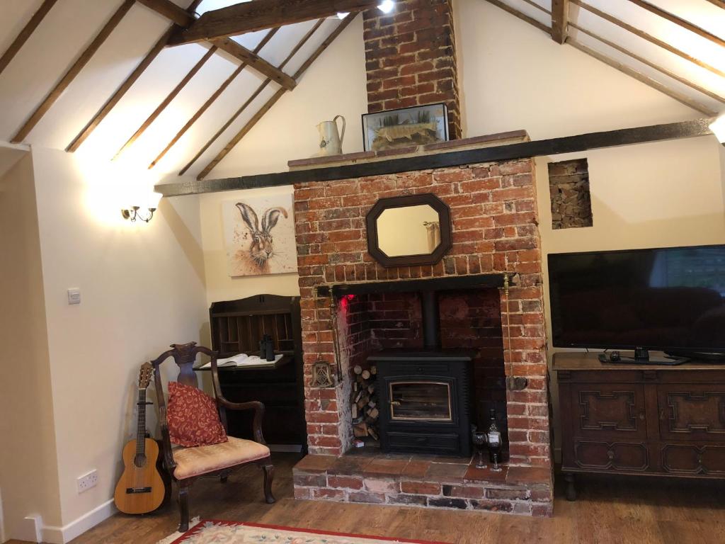 a living room with a brick fireplace and a television at Marsh View Cottage, Aldeburgh in Aldeburgh