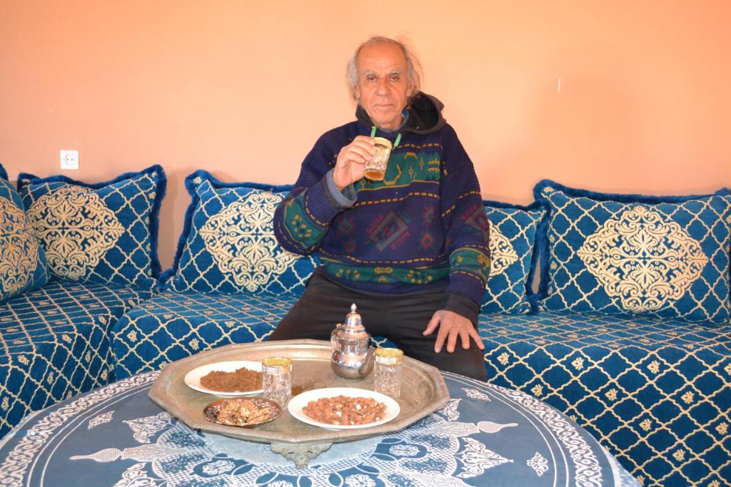 an older man sitting on a couch with a drink at GITE D'etape SIDI FLAH in Sidi Flah