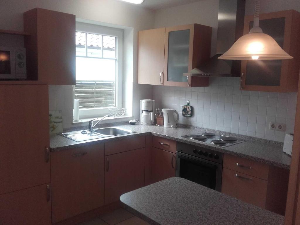 cocina con armarios marrones, fregadero y ventana en Ferienhaus Berger, en Timmendorfer Strand
