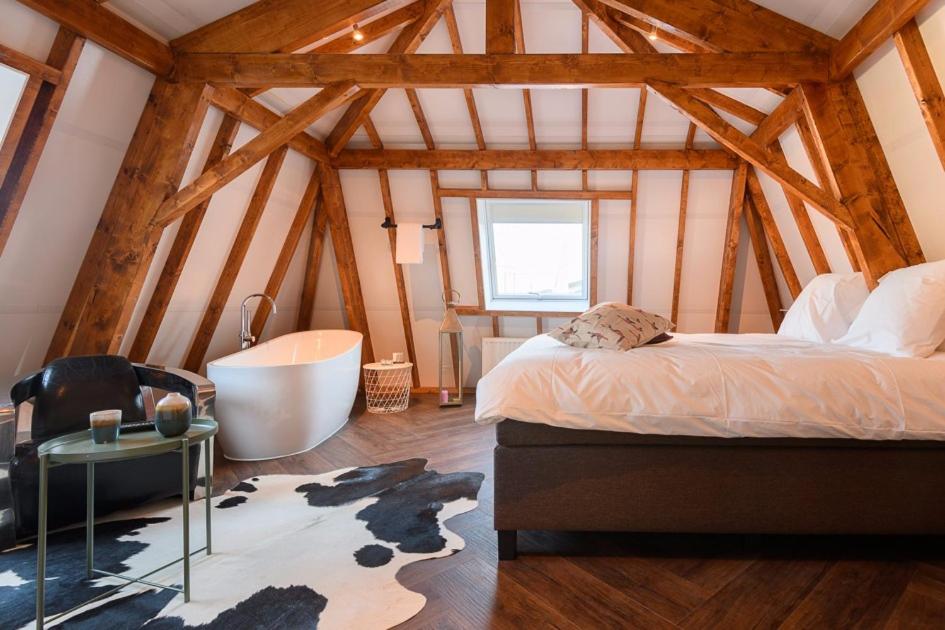 um quarto com uma cama e uma banheira num quarto em Hostellerie Horst em Horst