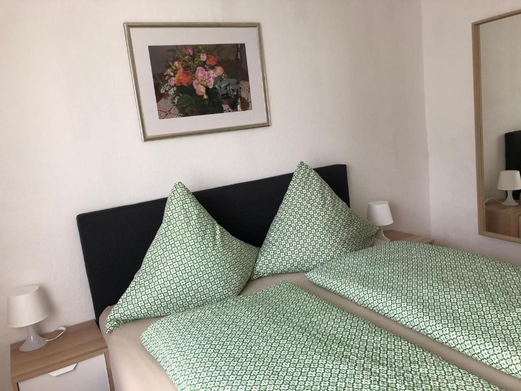 a bed with green pillows and a picture on the wall at Gästehaus Ziemons in Cochem