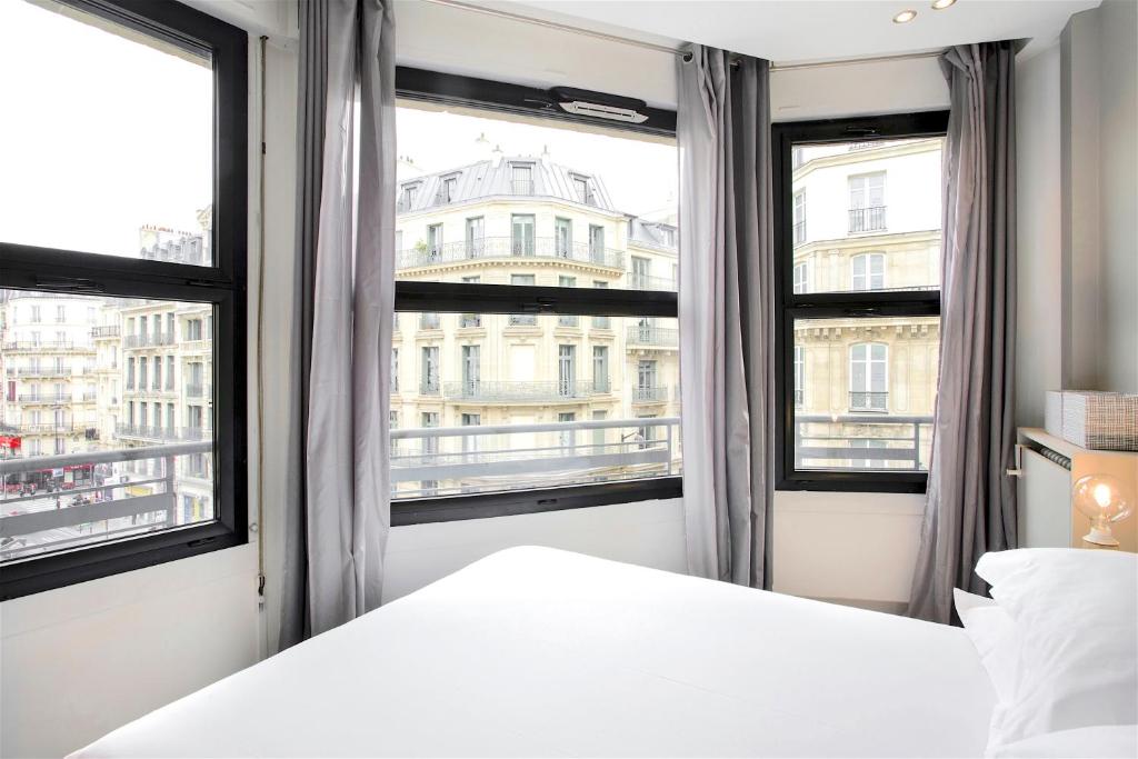 パリにあるApartment Opéra / Galeries Lafayetteのベッドルーム1室(ベッド1台、大きな窓2つ付)